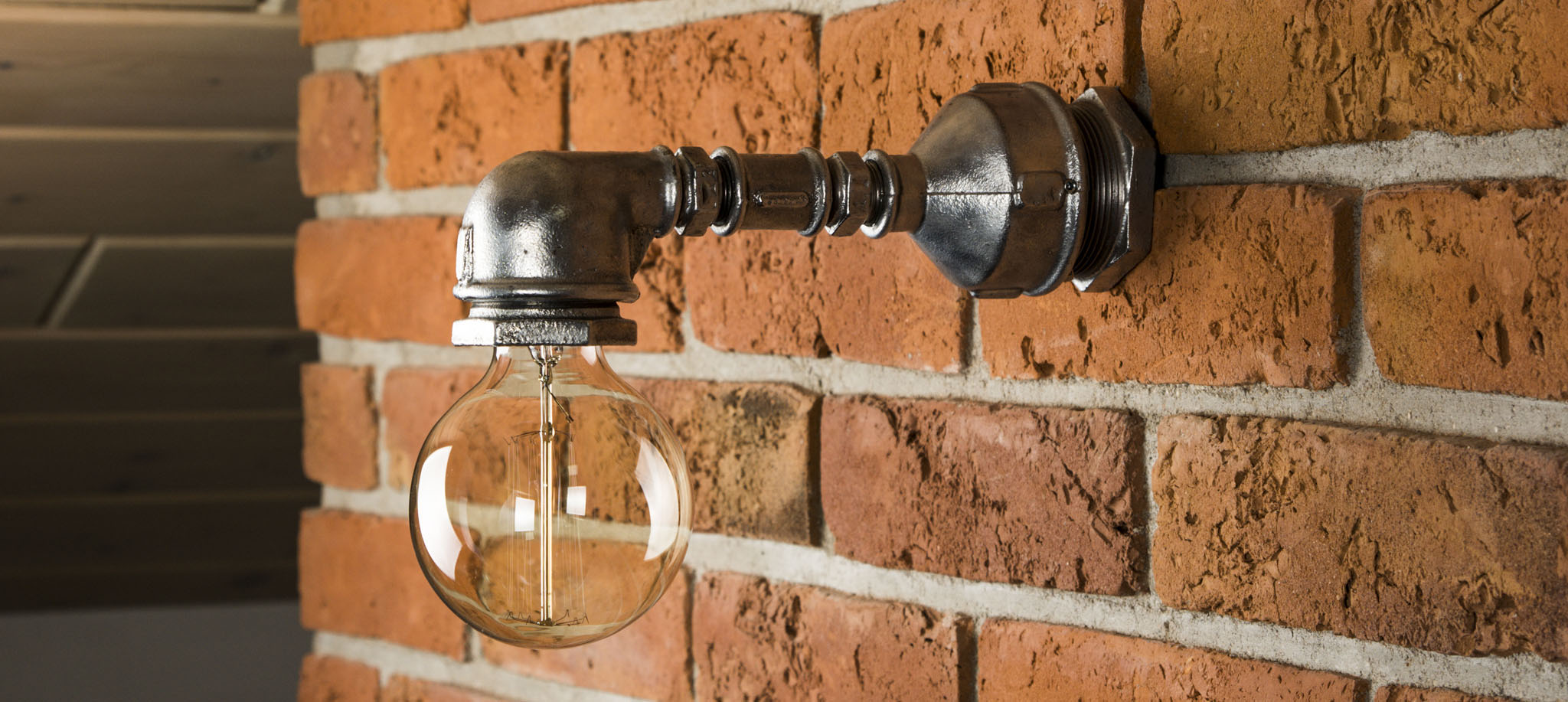 Industrialna Lampa z Rur - Kinkiet ścienny w kolrze srebrnym na tle ceglanej ściany